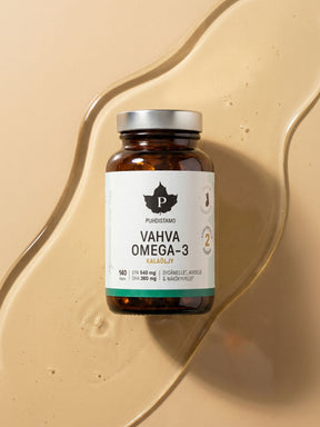 Puhdistamon Vahva Omega-3 140 kapselipurkki kalaöljyn päällä beigellä taustalla