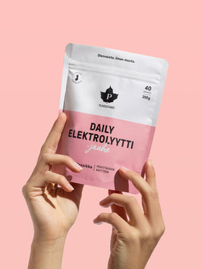 Nainen pitää käsissään Puhdistamon Daily Elektrolyyttijauhepussia