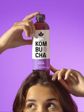 Nainen pitää päänsä päällä Puhdistamon Luomu Kombucha Goji-passion pulloa